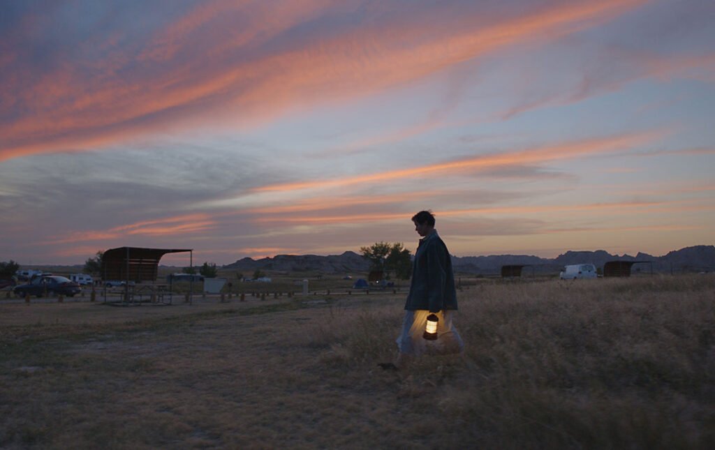 Fern (Frances McDormand) caminando al amanecer con una lámpara en mano en Nomadland.